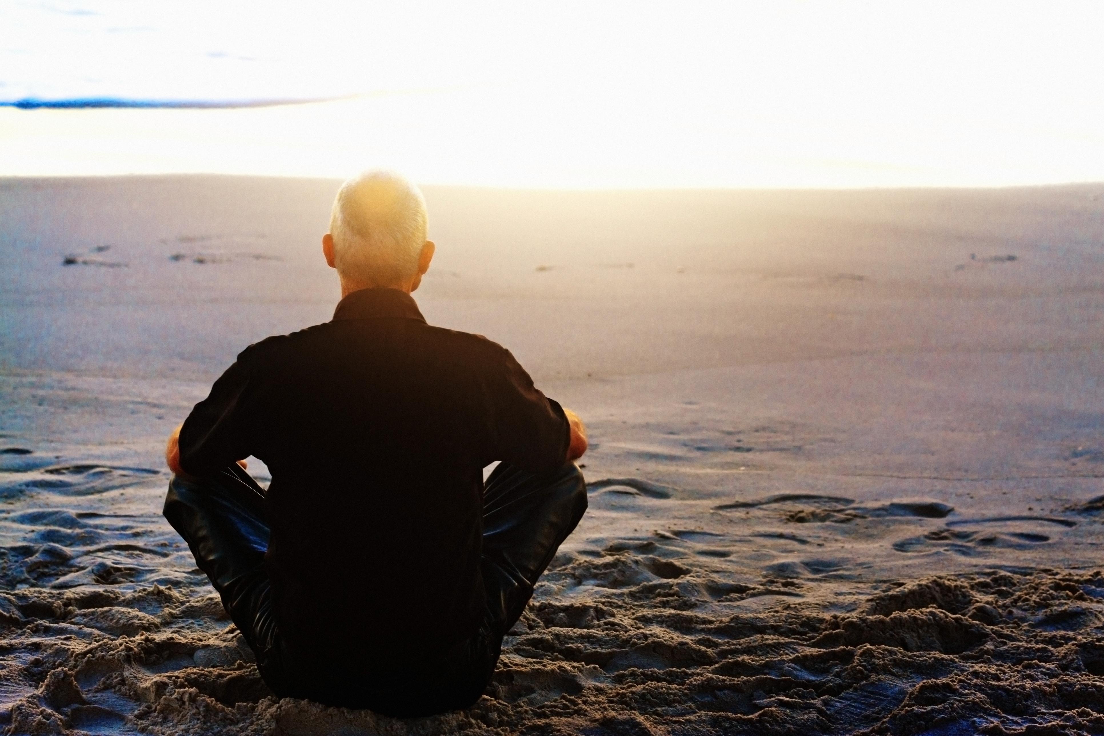 man meditating on beach